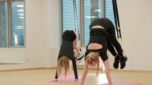 En grupp av personer, en kvinna och en man är utbildning armar och ben med fitness remmar i gymmet. — Stockvideo