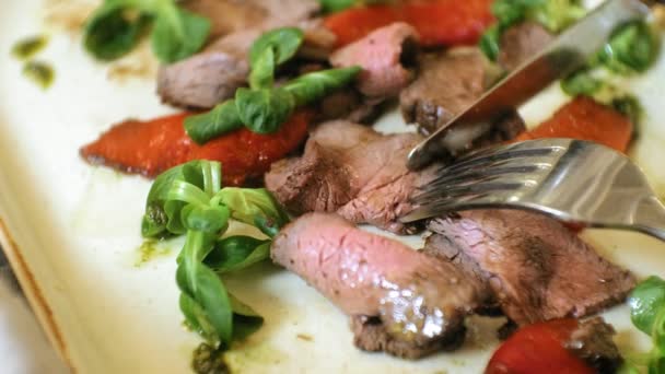 Tiro de cerca: un sabroso plato de carne en un plato, carne asada de res con pimientos dulces y hojas de ensalada verde . — Vídeo de stock
