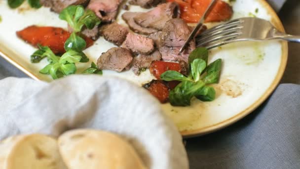 Tiro de cerca: un sabroso plato de carne en un plato, carne asada de res con pimientos dulces y hojas de ensalada verde . — Vídeos de Stock