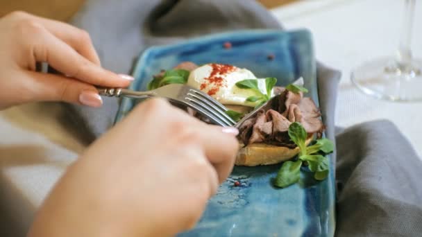 Tiro de cerca: un delicioso sándwich con carne de res, huevo escalfado y hojas de lechuga, bruschetta . — Vídeos de Stock