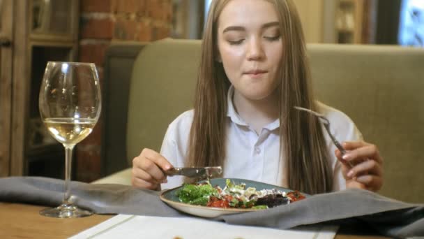 美しい金髪の女性 野菜サラダを食べるレストランで白ワインを飲んでカトラリー フォークとナイフを使ってします 菜食主義者 肖像画 — ストック動画