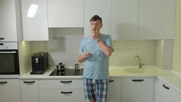 Un uomo in pigiama che beve acqua in cucina. Buongiorno. — Video Stock