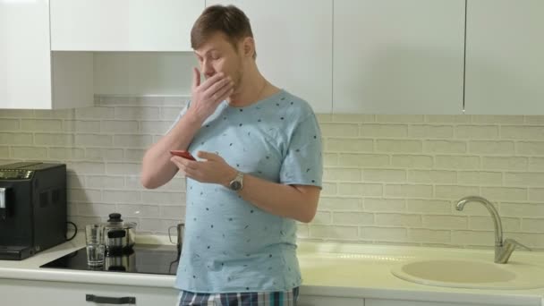 En man i pyjamas dricks vatten i köket. Morgon — Stockvideo
