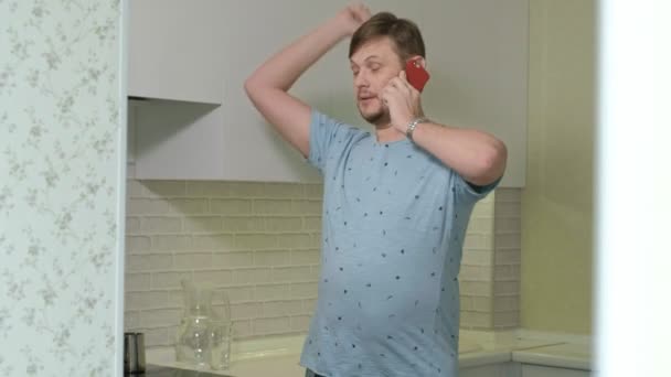 Ένας άντρας με πιτζάμες να πίνει νερό στην κουζίνα. Πρωί — Αρχείο Βίντεο