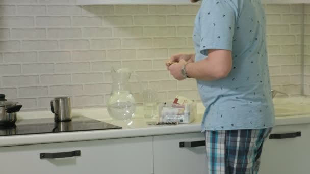 Egy férfi pizsama ivóvíz a konyhában. Reggel — Stock videók