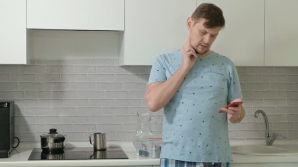 Ein Mann im Schlafanzug trinkt Wasser in der Küche. Morgen — Stockvideo