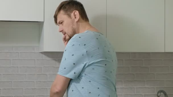 Człowiek w piżamie wody pitnej w kuchni. Rano — Wideo stockowe