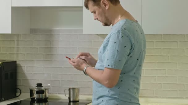 Pijamalı bir adam mutfakta su içiyor. Sabah — Stok video
