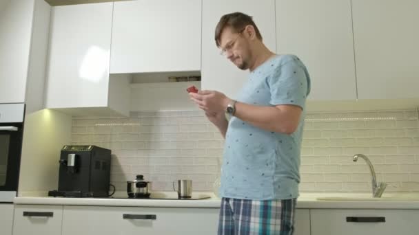 Un hombre en pijama bebiendo agua en la cocina. Buenos días. — Vídeos de Stock