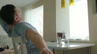Pijamalı bir adam mutfakta su içiyor. Sabah