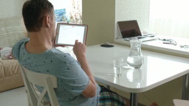 Pijamalı bir adam mutfakta su içiyor. Sabah