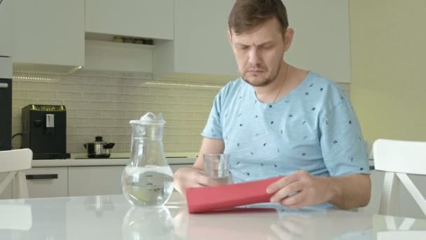 Un hombre en pijama bebiendo agua en la cocina. Buenos días. — Vídeos de Stock