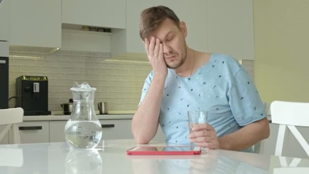 Um homem de pijama a beber água na cozinha. Bom dia. — Vídeo de Stock