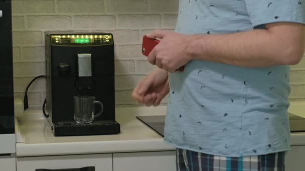 Un hombre en pijama bebiendo agua en la cocina. Buenos días. — Vídeo de stock