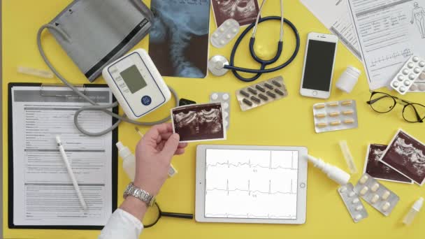 Vista superior del escritorio de los terapeutas, resultados del ECG en una tableta de computadora, ultrasonido, medicina y concepto de atención médica — Vídeos de Stock