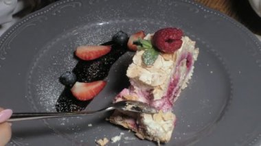 yakın çekim: ahududu ile beze rulo, mavi plaka üzerinde Tepesi ve çilek ile süslenmiş