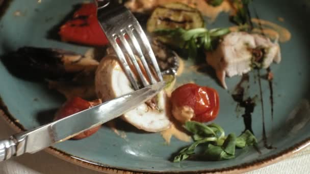 Close-up schieten: kip gebakken in spek met groenten, met saus en groene salade op een blauw bord — Stockvideo