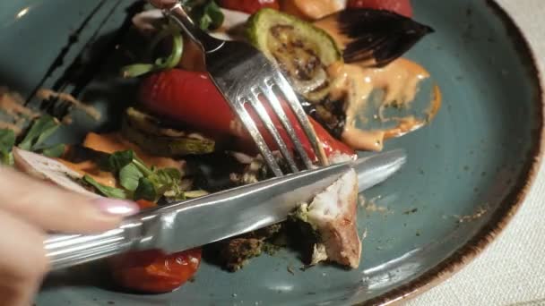 Close-up schieten: kip gebakken in spek met groenten, met saus en groene salade op een blauw bord — Stockvideo