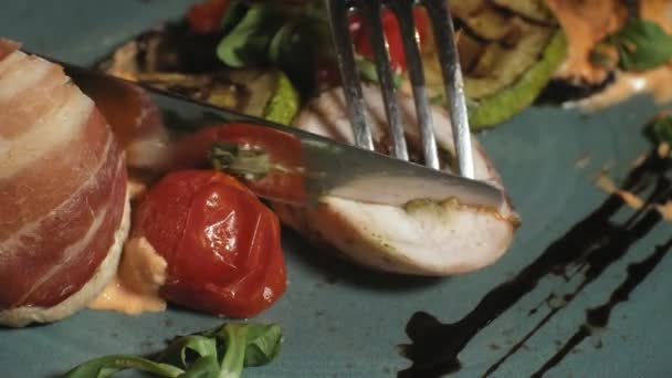Närbild skytte: kyckling bakad i bacon med grönsaker, sås och gröna sallad på en blå tallrik — Stockvideo