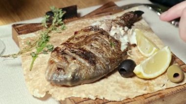 yakın çekim çekim: ızgara balık dorylo zeytin ve bir dilim limon pide üzerinde.