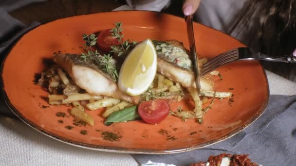 Tiro de cerca: salmón al horno con especias, papas fritas y una rebanada de limón en un plato de naranja — Vídeos de Stock