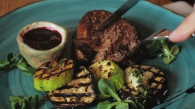 yakın çekim çekim: pişmiş et ve mavi bir plaka üzerinde kırmızı soslu ızgara sebze