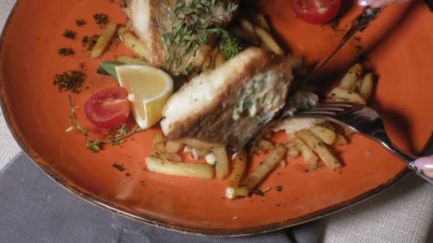 Close-up shooting: baked salmon with spices, french fries and a slice of lemon on an orange plate — Stock Video