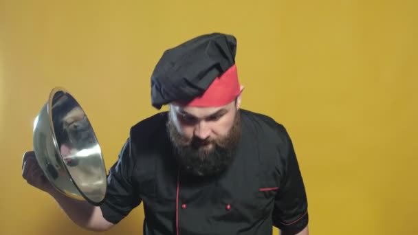 Cocinar en un traje negro sobre un fondo amarillo — Vídeo de stock