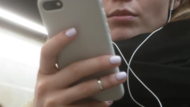 Joven morena mujer utiliza un teléfono con auriculares — Vídeo de stock