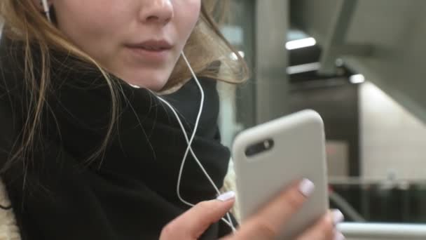Fiatal barna nő használ egy telefont fejhallgatóval — Stock videók