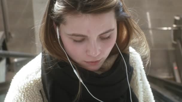 Νεαρή μελαχρινή γυναίκα χρησιμοποιεί ένα τηλέφωνο με ακουστικά — Αρχείο Βίντεο