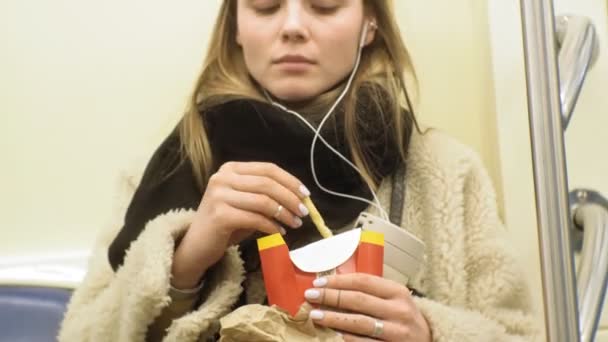 Jeune femme brune monte dans les transports en commun, utilise le téléphone avec écouteurs — Video