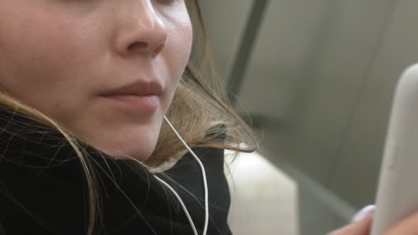 Jonge brunette vrouw maakt gebruik van een telefoon met een koptelefoon — Stockvideo