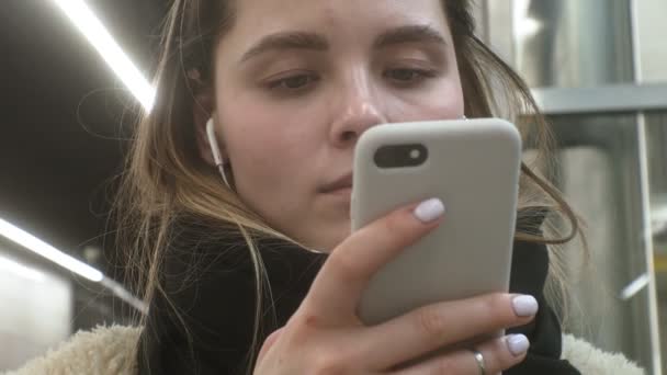 Joven morena mujer utiliza un teléfono con auriculares — Vídeo de stock