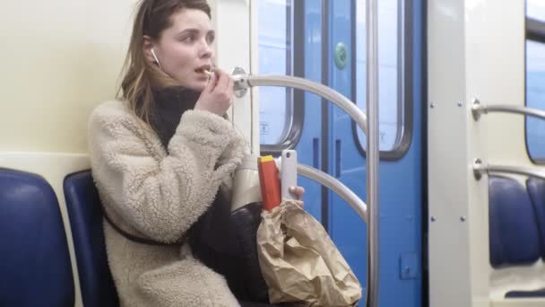 Jovem morena mulher monta em transportes públicos, usa o telefone com fones de ouvido — Vídeo de Stock