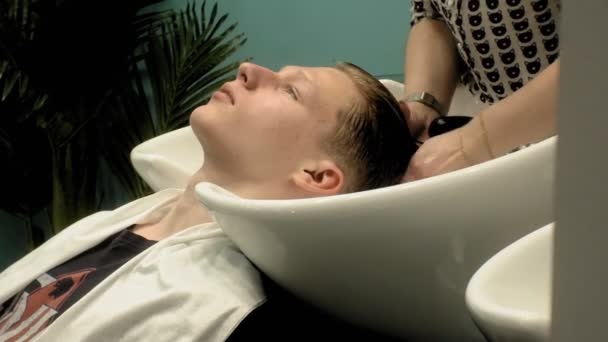 Fryzjer myje głowę chłopca w salonie — Wideo stockowe