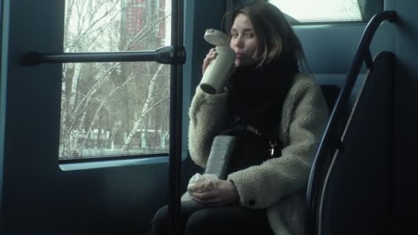Jeune femme brune monte dans les transports en commun, utilise le téléphone avec écouteurs — Video