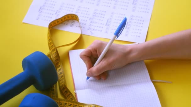 Calendario de deportes, comida saludable, disparos en un fondo amarillo vista superior — Vídeo de stock