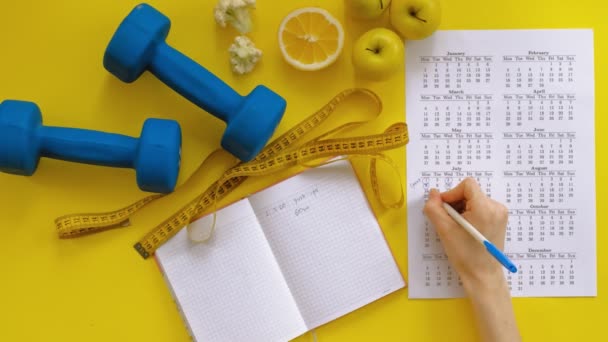 Sportkalender, hälsosam mat, skytte på en gul bakgrund uppifrån — Stockvideo