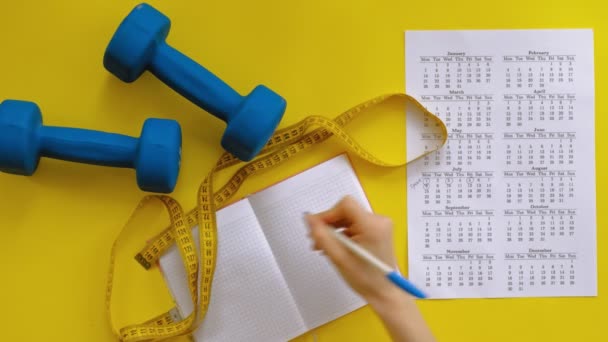 Sportkalender, gezond eten, schieten op een gele achtergrond bovenaanzicht — Stockvideo