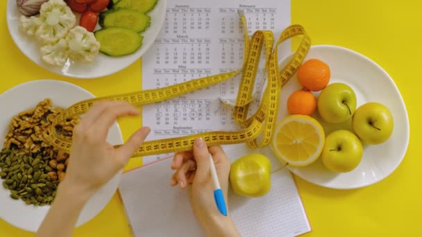 Calendario de deportes, comida saludable, disparos en un fondo amarillo vista superior — Vídeos de Stock