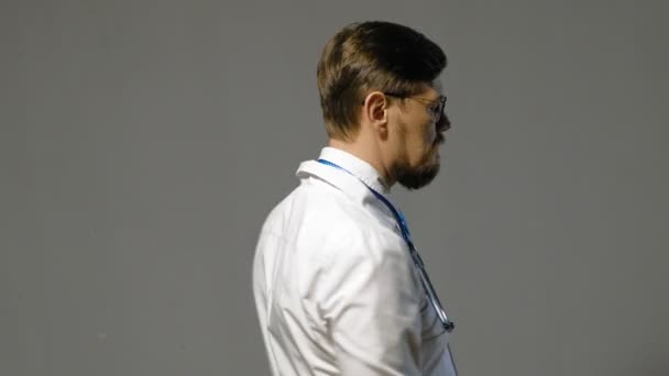 Doctor hombre en bata blanca sobre fondo gris, concepto de medicina — Vídeos de Stock