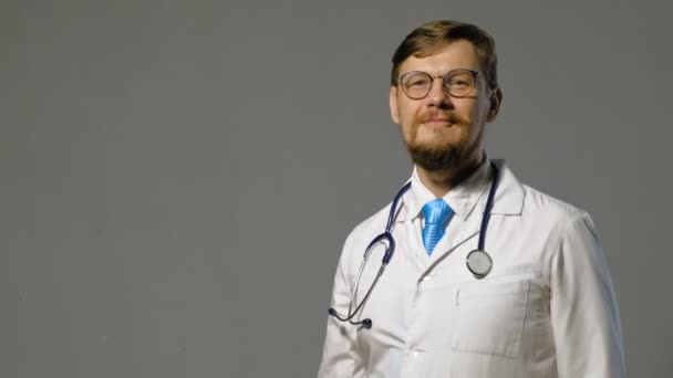 Lékař muž v bílém plášti na šedém pozadí, koncepce medicíny — Stock video