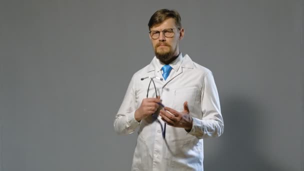 Doctor hombre en bata blanca sobre fondo gris, concepto de medicina — Vídeo de stock