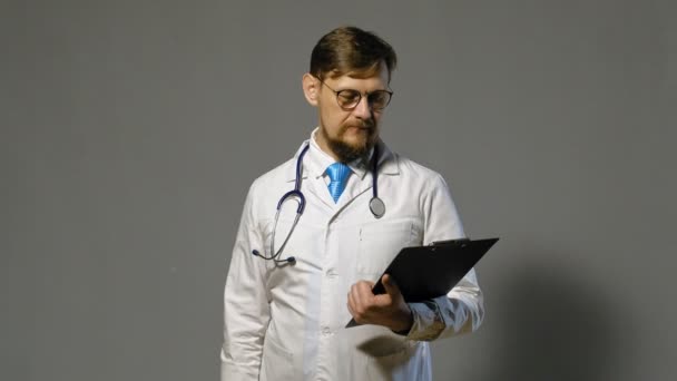 Doctor hombre en bata blanca sobre fondo gris, concepto de medicina — Vídeos de Stock