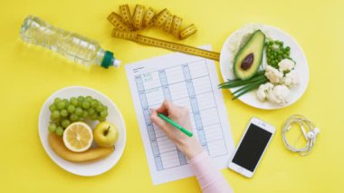 Sağlıklı gıda, diyet, üst görünüm, sarı arka plan kavramı bir fitness takvimi tutmak
