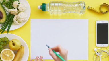 Sağlıklı gıda, diyet, üst görünüm, sarı arka plan kavramı bir fitness takvimi tutmak