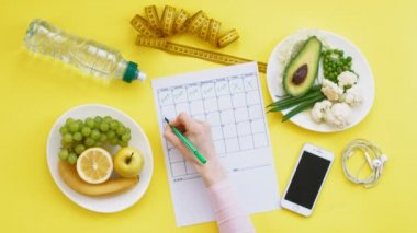 Sağlıklı gıda, diyet, üst görünüm, sarı arka plan kavramı bir fitness takvimi tutmak