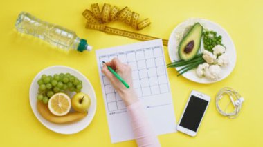 Sağlıklı gıda, diyet, üst görünüm, sarı arka plan kavramı bir fitness takvimi tutmak