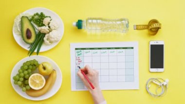 Sağlıklı gıda, diyet, üst görünüm, sarı arka plan kavramı bir fitness takvimi tutmak